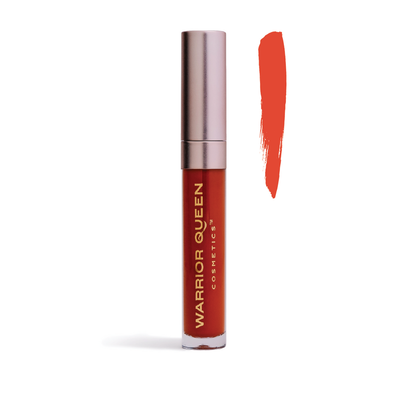 Blaze orange lip stain container labeled with gold Warrior Queen Cosmetics brand text and to the right of the container a vertical brush stroke of blaze orange color sample.