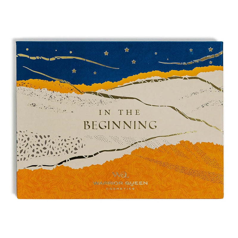 In The Beginning eyeshadow makeup palette cover with blue, beige, and gold stars and sand illustration.
